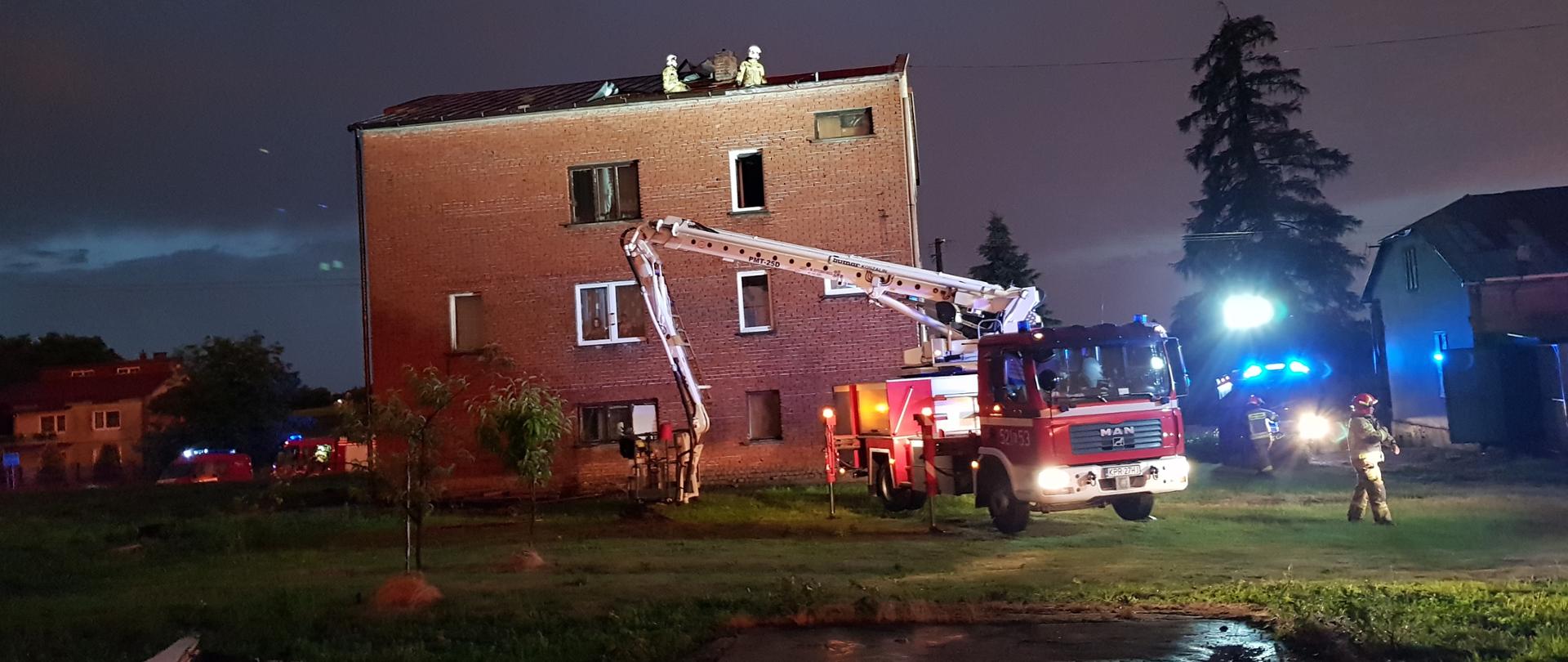 Strażacy zabezpieczają zerwany dach na budynku mieszkalnym, na pierwszym planie podnośnik hydrauliczny