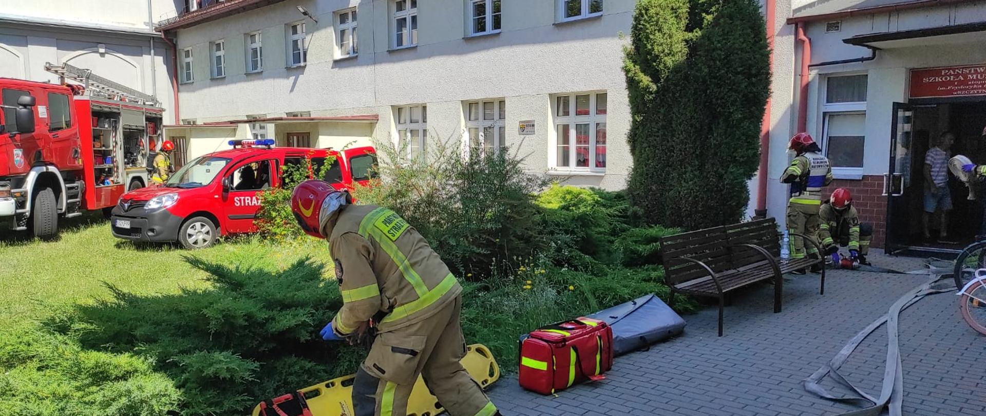 Zdjęcie przedstawia strażaków w trakcie ćwiczenia bojowego w w Państwowej Szkole Muzycznej w Szczytnie