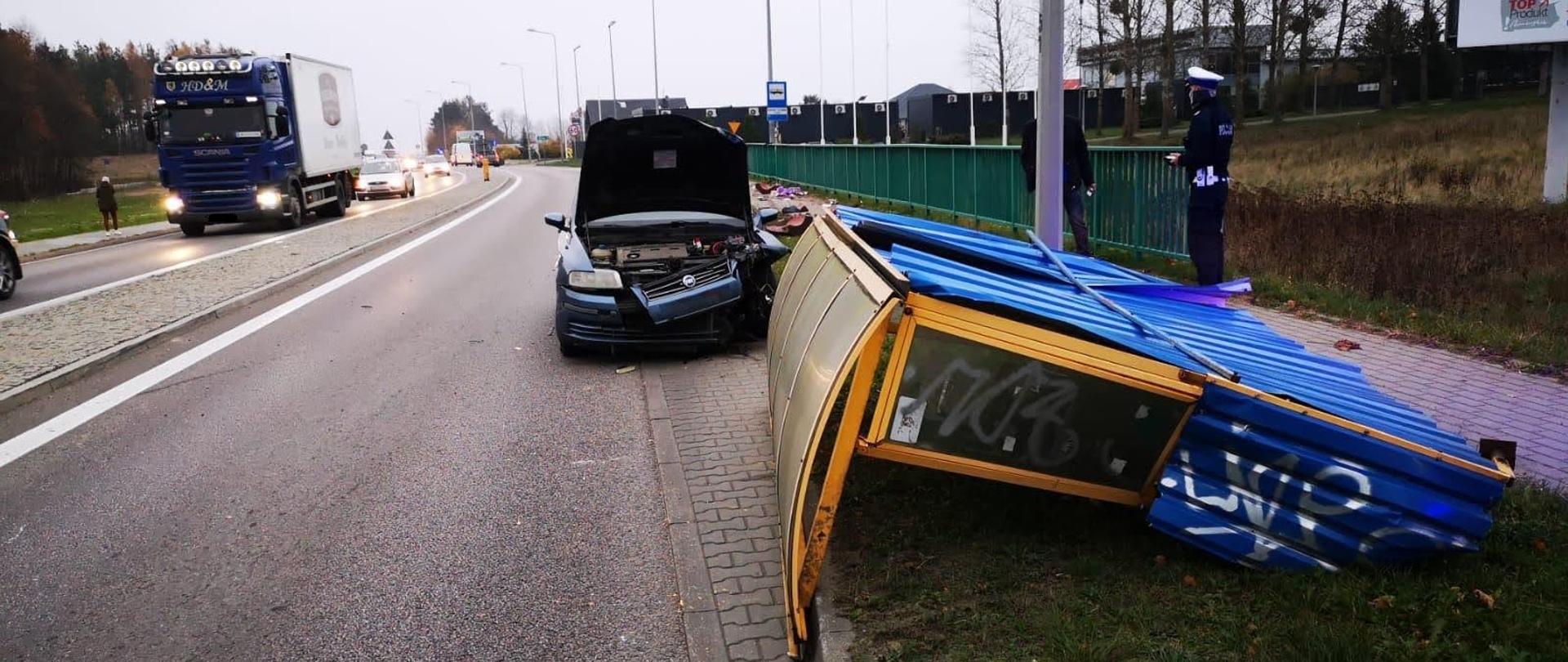 Uszkodzony przód samochodu i przewrócona wiata przystanku
