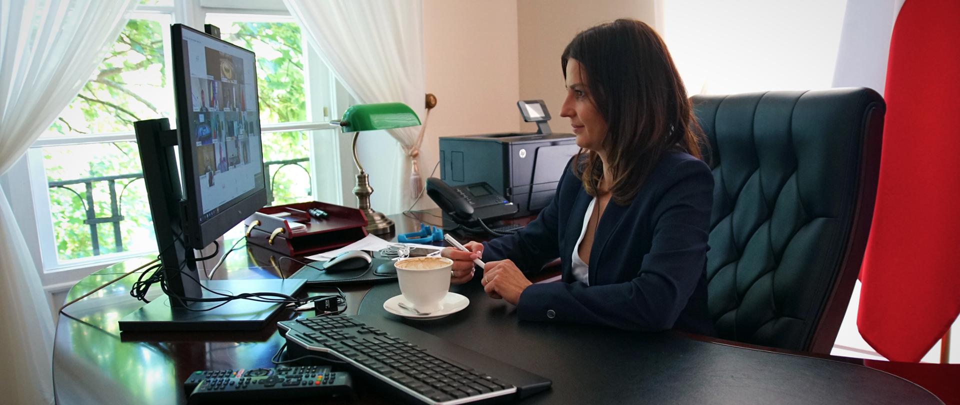 Minister Sportu Danuta Dmowska-Andrzejuk uczestniczy w wideokonferencji zza swojego biurka.