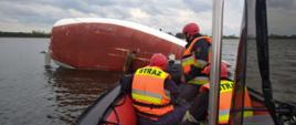 Zdjęcie przedstawia przewróconą żaglówkę na Jeziorze Pątnowskim oraz strażaków znajdujących się w łodzi
