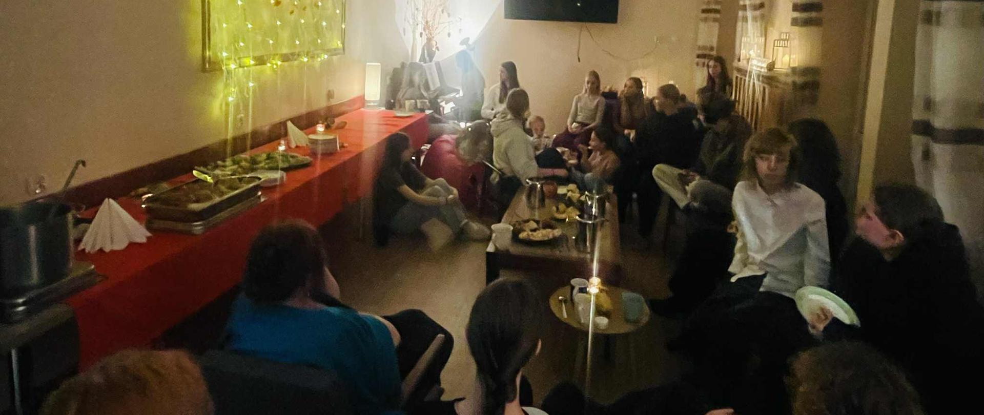 Na zdjęciu zgromadzona wokół stolików grupa dziewcząt. Wszystkie rozmawiają z koleżankami.