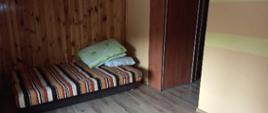 Na zdjęciu widać pomieszczenie. W pomieszczeniu łóżka. Na ścianie boazeria drewniana. Na podłosze panel podłogowy. Zdjęcie zrobione w ciągu dnia.
