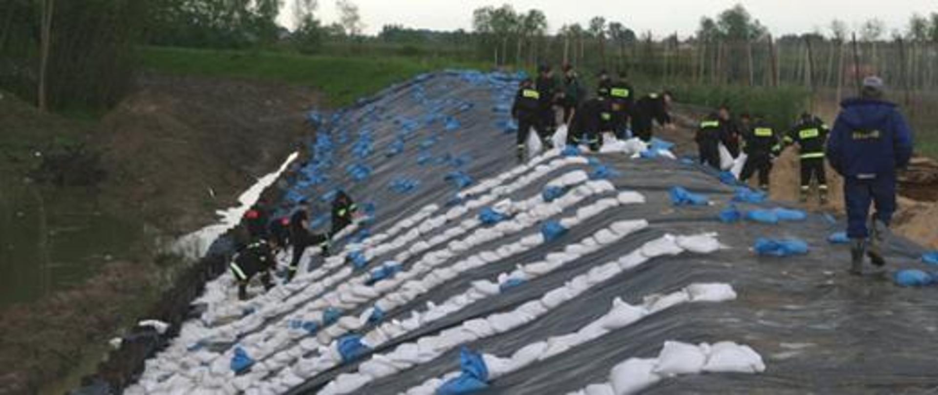 Na zdjęciu działania służb podczas powodzi - umacnianie wałów workami z piaskiem