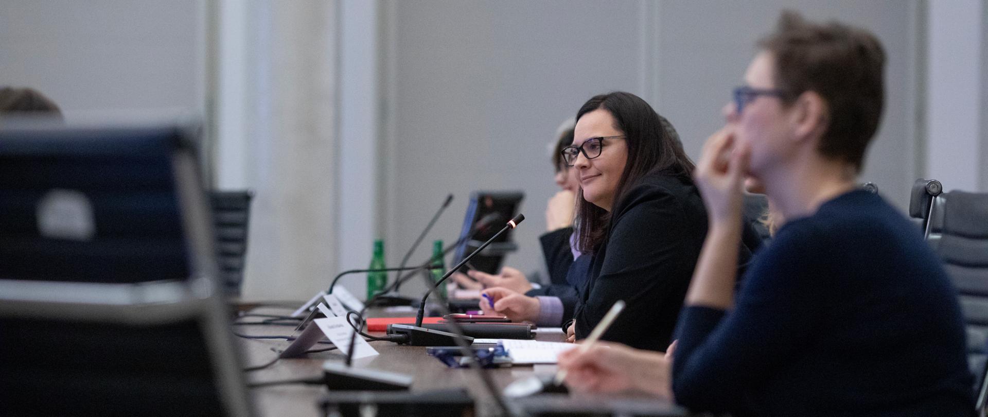 Wiceminister Małgorzata Jarosińska-Jedynak siedzi przy stole konferencyjnym