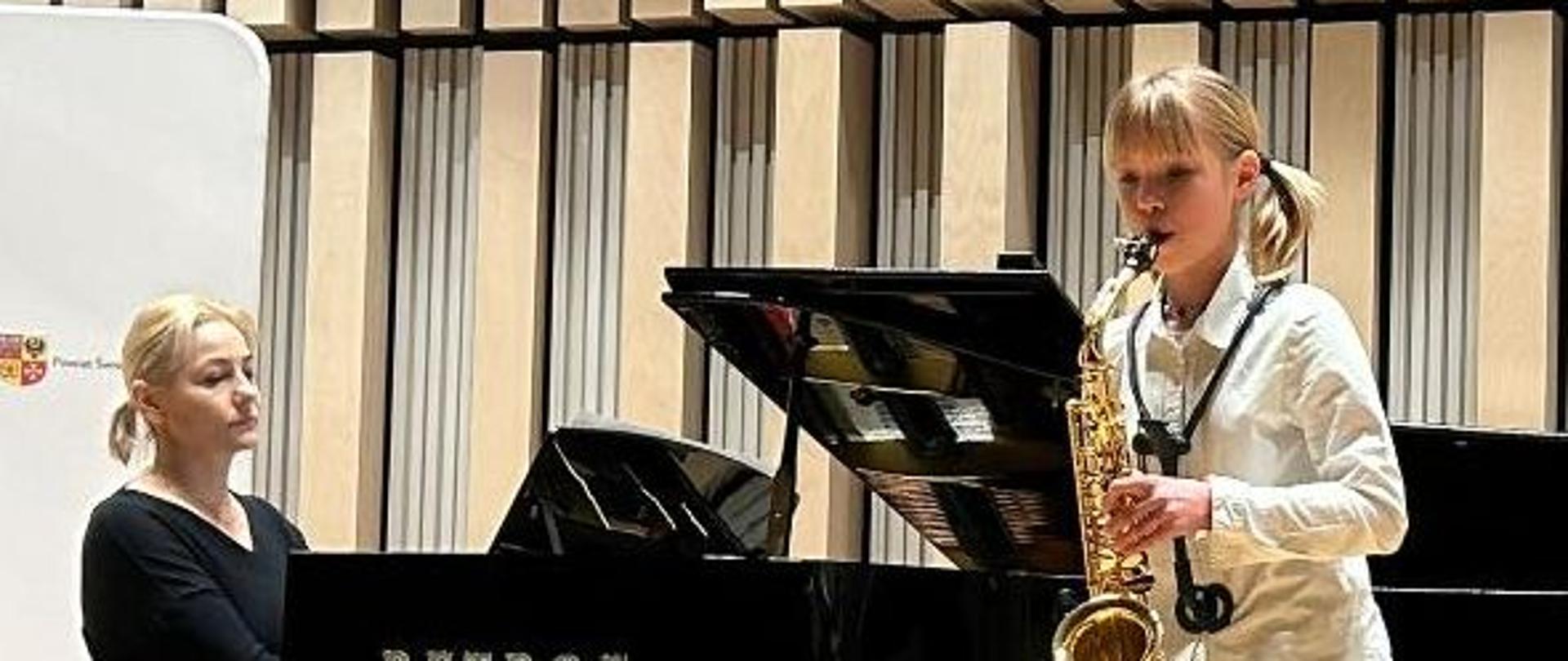 Laura Nowak gra na saksofonie. Akompaniuje jej przy fortepianie pani Elwira Janiec-Krajewska.