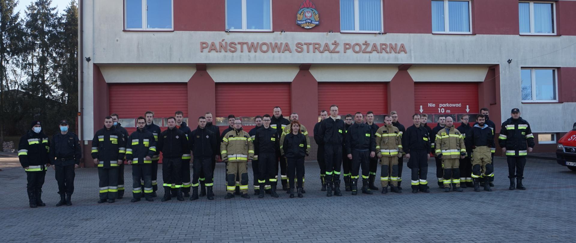 Umundurowani strażacy OSP z komisja egzaminacyjna przed budynkiem JRG Miechów.