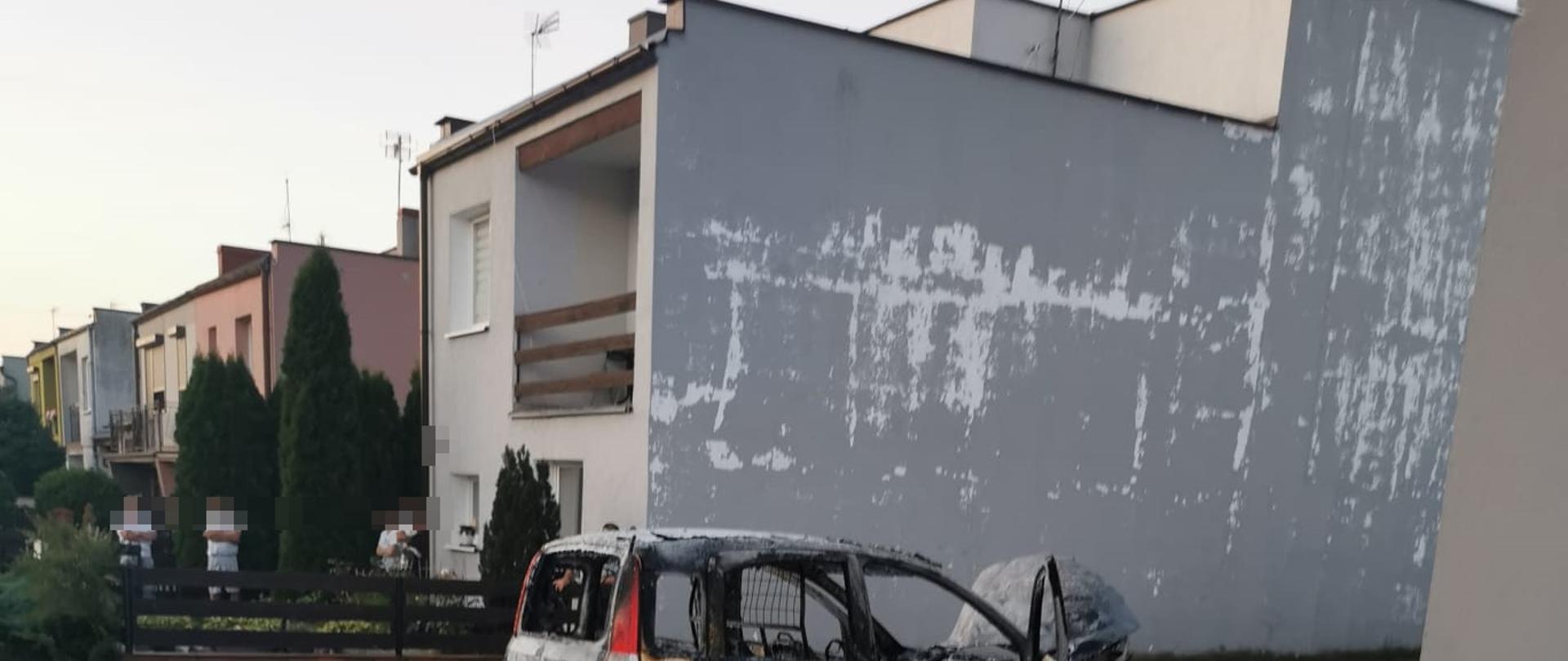 Na zdjęciu widać spalony samochód oraz strażaków 