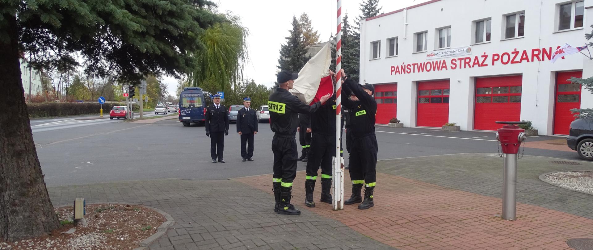 strażacy wciągają flagę na maszt 