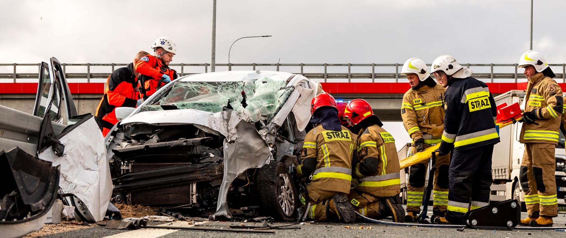 Strażacy wraz z ratownikami medycznymi pracują nad uwolnieniem osoby zakleszczonej w pojeździe