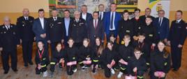 uczestnicy uroczystości wręczenia promes dla młodzieżowych drużyn pożarniczych pozują do zdjęcia zbiorowego wśród nich młodzież mdp, strażacy druhowie, posłowie i senatorowie RP, przedstawiciele władz samorządowych