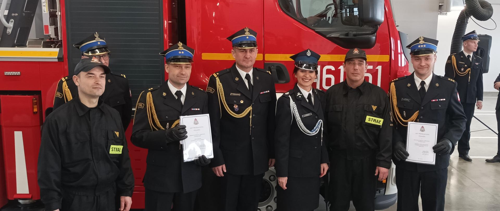 Pani poseł w towarzystwie kilku strażaków, po wręczeniu aktów przekazania pojazdów. W tle auto pożarnicze.