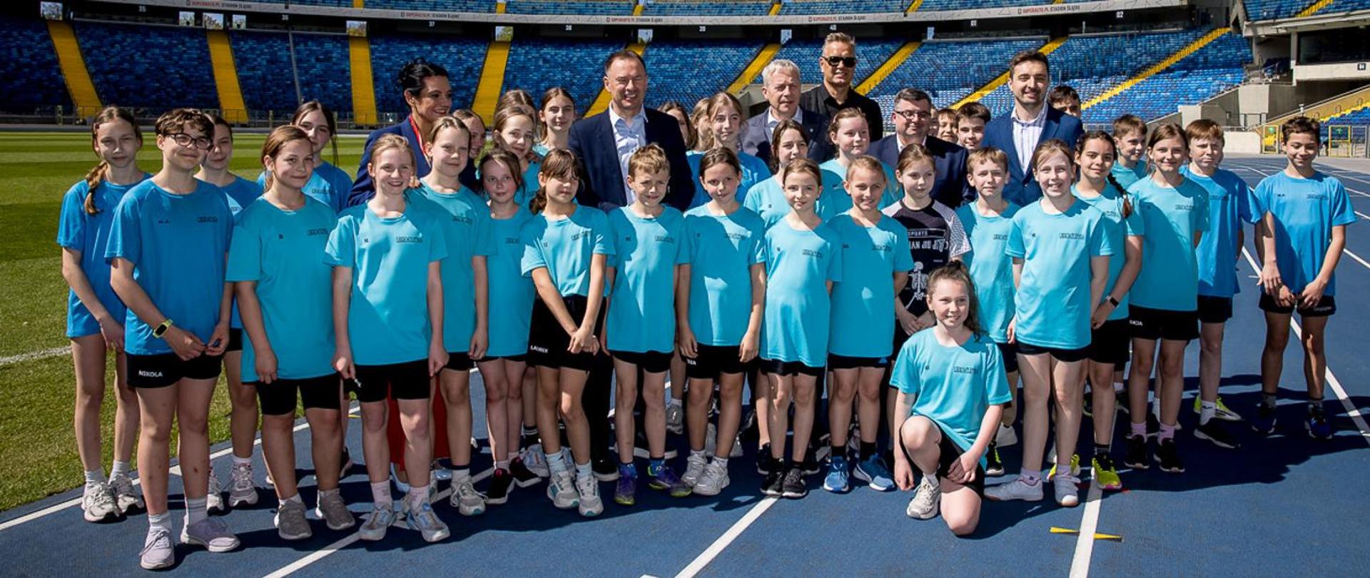 Group photo of young athletes on the track at the stadium.