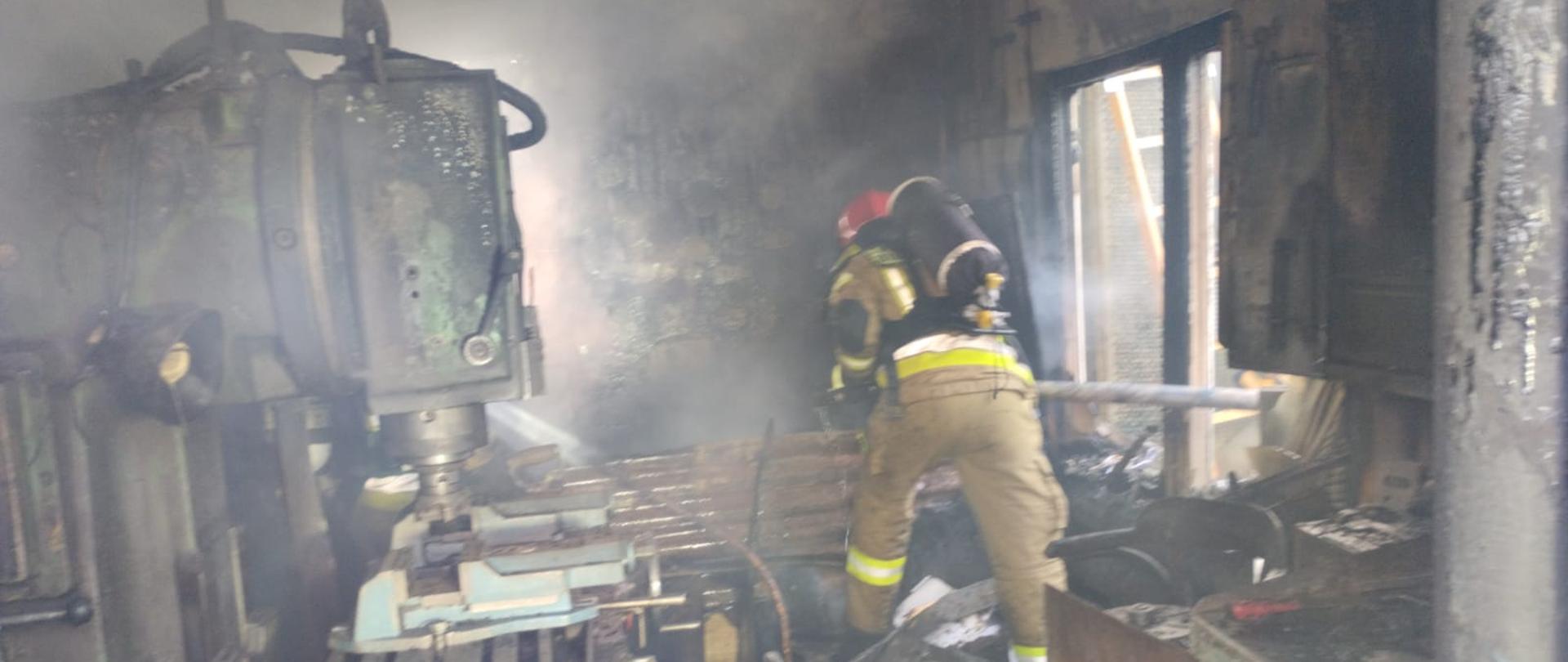 Na zdjęciu widać strażaków pracujących wewnątrz spalonego warsztatu 