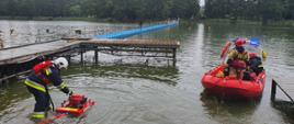 Strażak odpalający motopompę pływającą na brzegu Wyspy Edwarda i zastęp na łodzi OSP Zaniemyśl dobijający do brzegu Wyspy Edwarda.