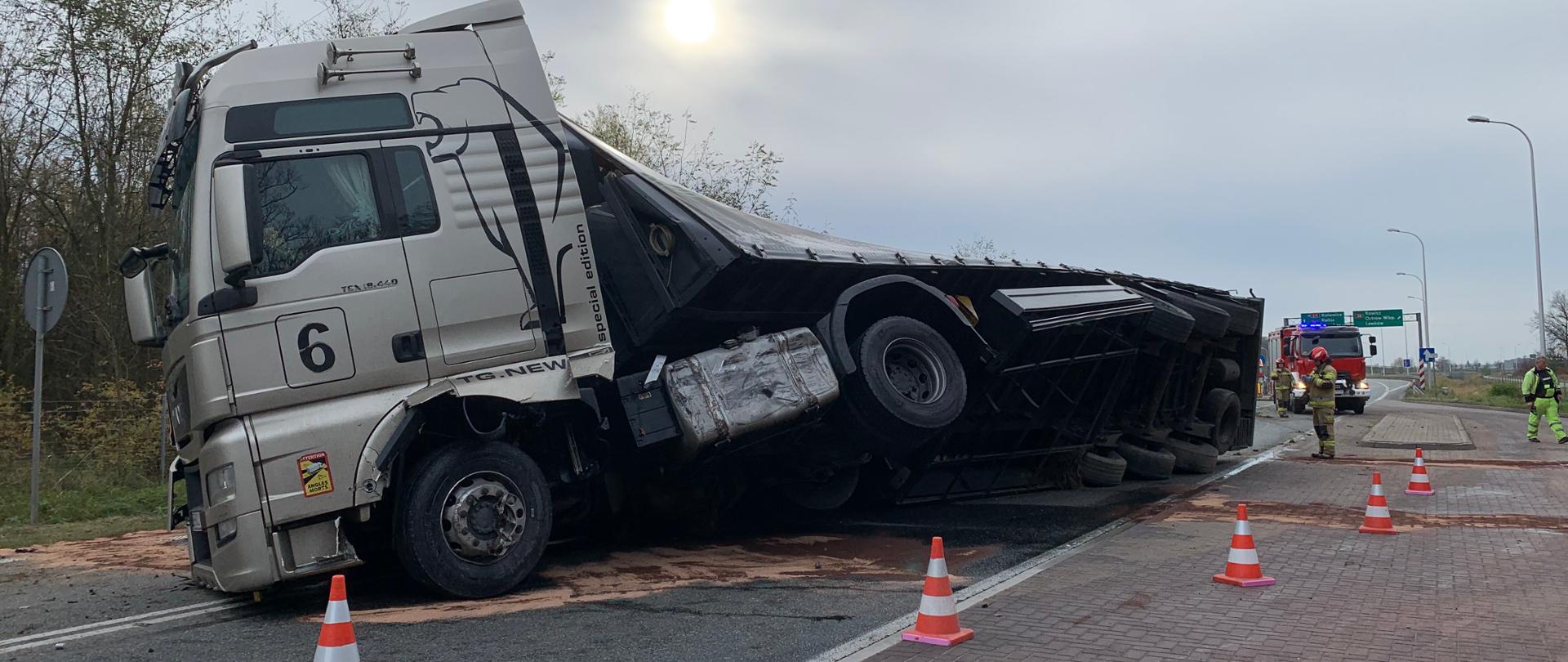 Ciężarówka leżąca na boku, strażacy w akcji