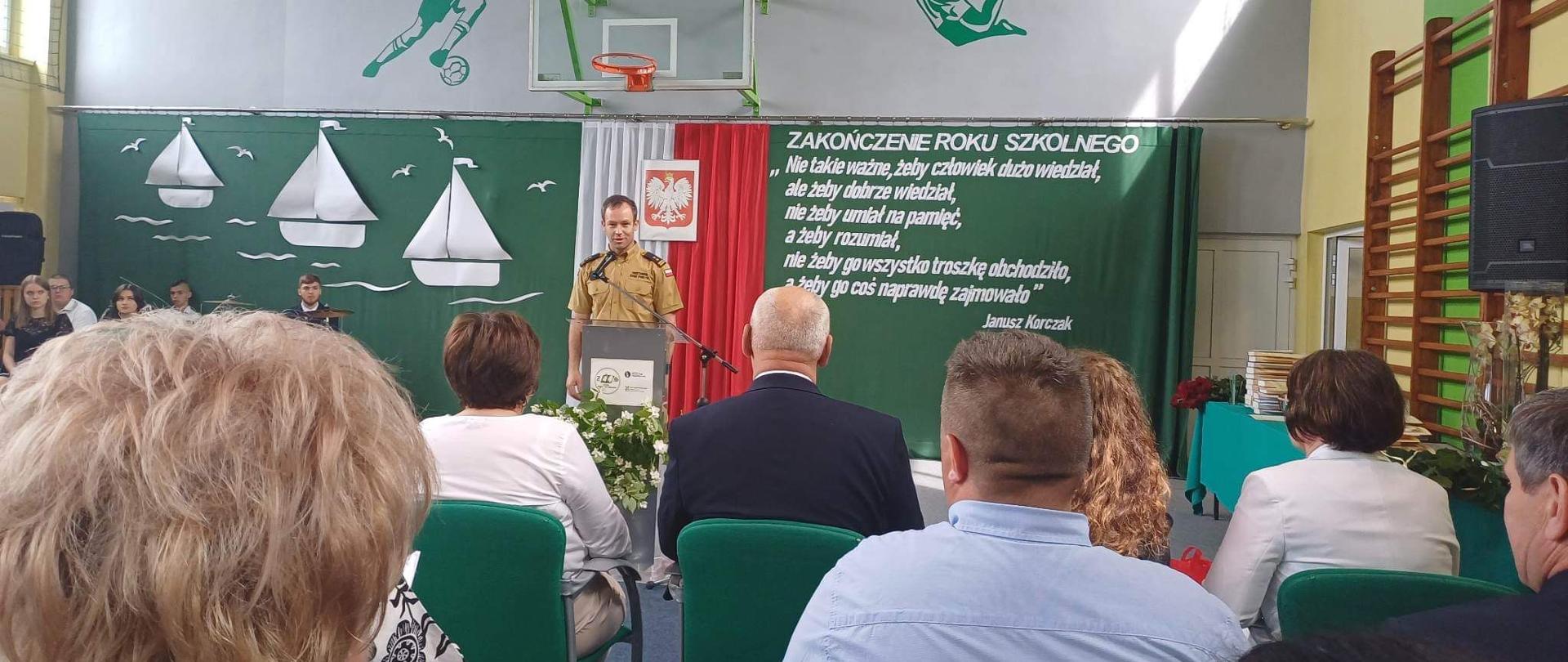 Zakończenie roku szkolnego 2022/2023 w Zespole Szkół Centrum Kształcenia Rolniczego im. Władysława Stanisława Reymonta w Sokołowie Podlaskim - na zdjęciu strażak przemawia w sali gimnastycznej na zakończenie roku szkolnego