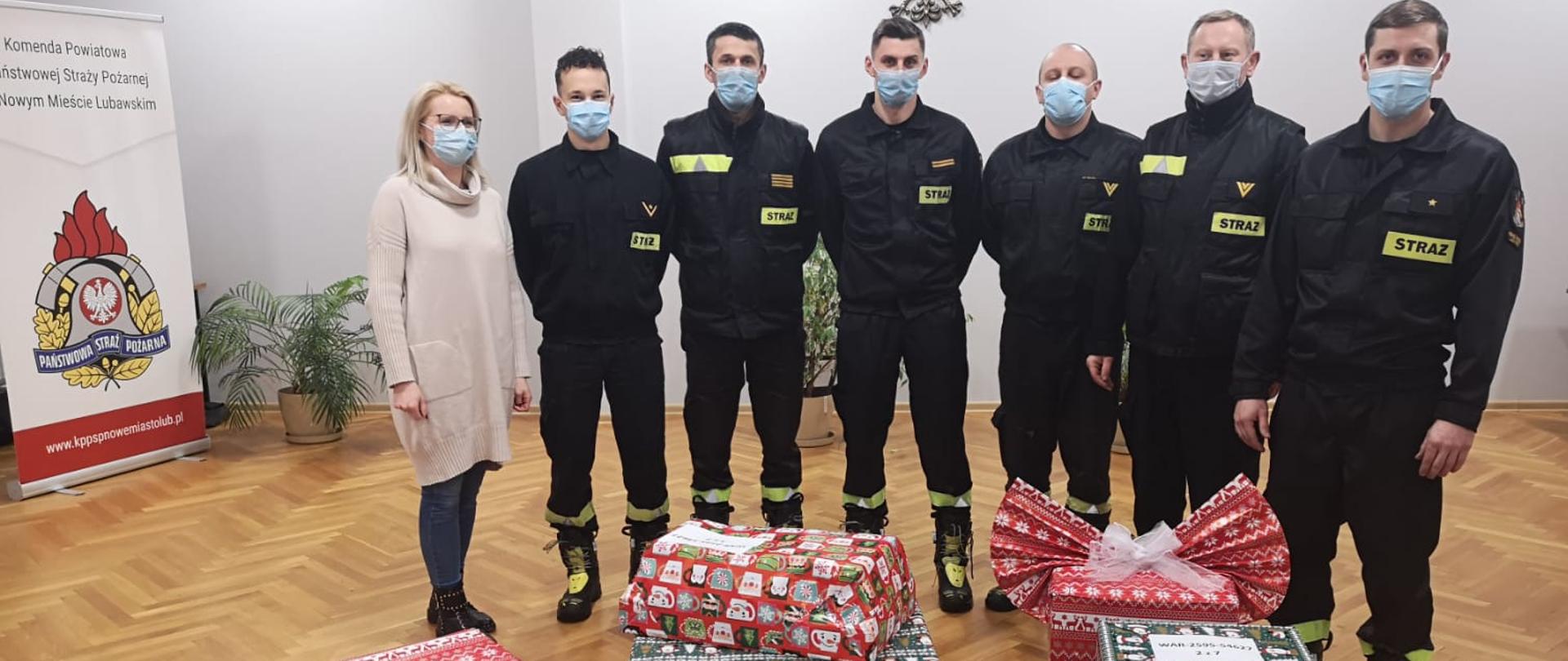Strażacy z paczkami prezentami na sali konferencyjnej w psp
