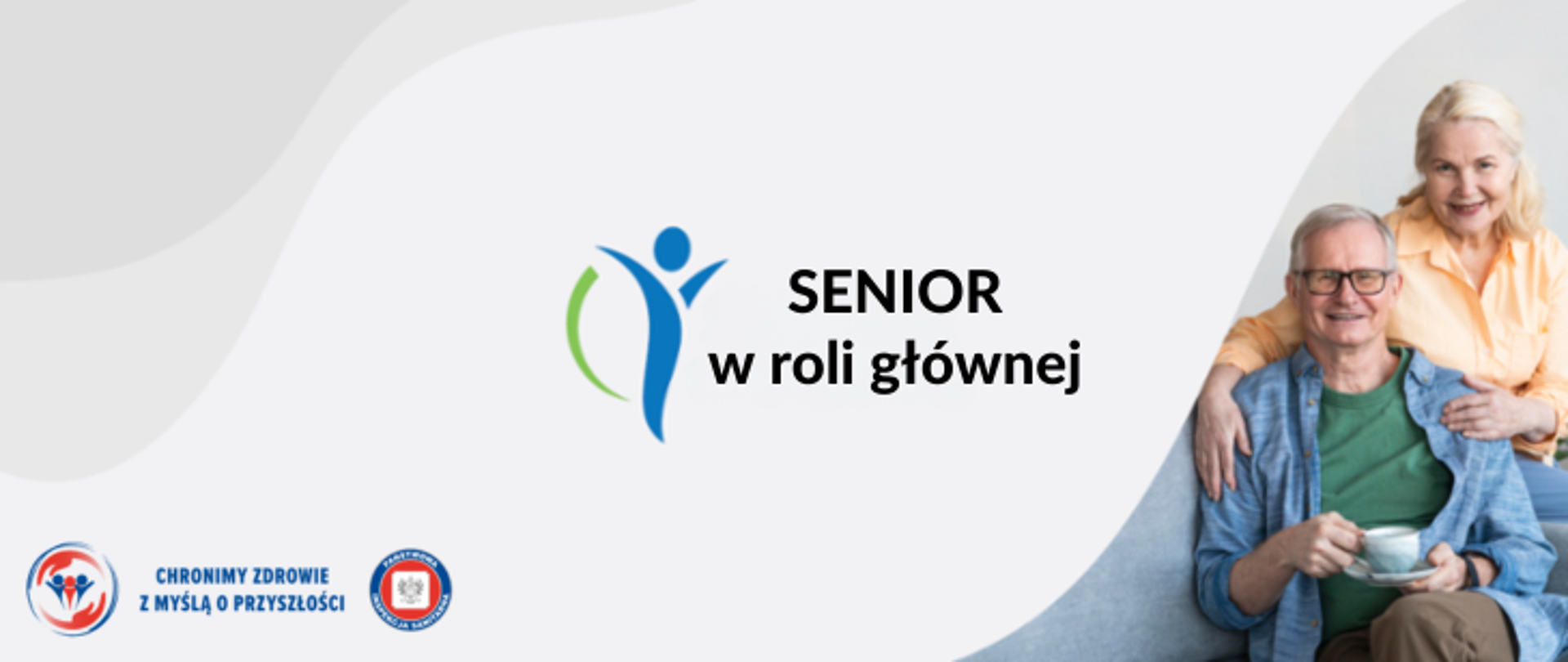 Na szarym tle na środku czarny napis: Senior w roli głównej wraz z niebiesko-zielonym logiem. Po prawej para seniorów kobieta w jasnych, długich włosach ubrana w pomarańczową koszulę przytula mężczyznę w okularach ubranego w zielony podkoszulek i niebieską rozpiętą koszulę. Mężczyzna trzyma w dłoni białą filiżankę na spodku. W lewym dolnym rogu logo Państwowej Inspekcji Sanitarnej wraz z hasłem Chronimy zdrowie z myślą o przyszłości. 