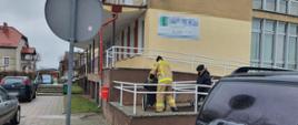 Strażacy z OSP Barwice po raz kolejny pomagają seniorom w ramach akcji „SzczepimySię”. Strażak ubrany w ubranie specjalne koloru piaskowego w wozi osobę niepełnosprawną do punktu szczepień.