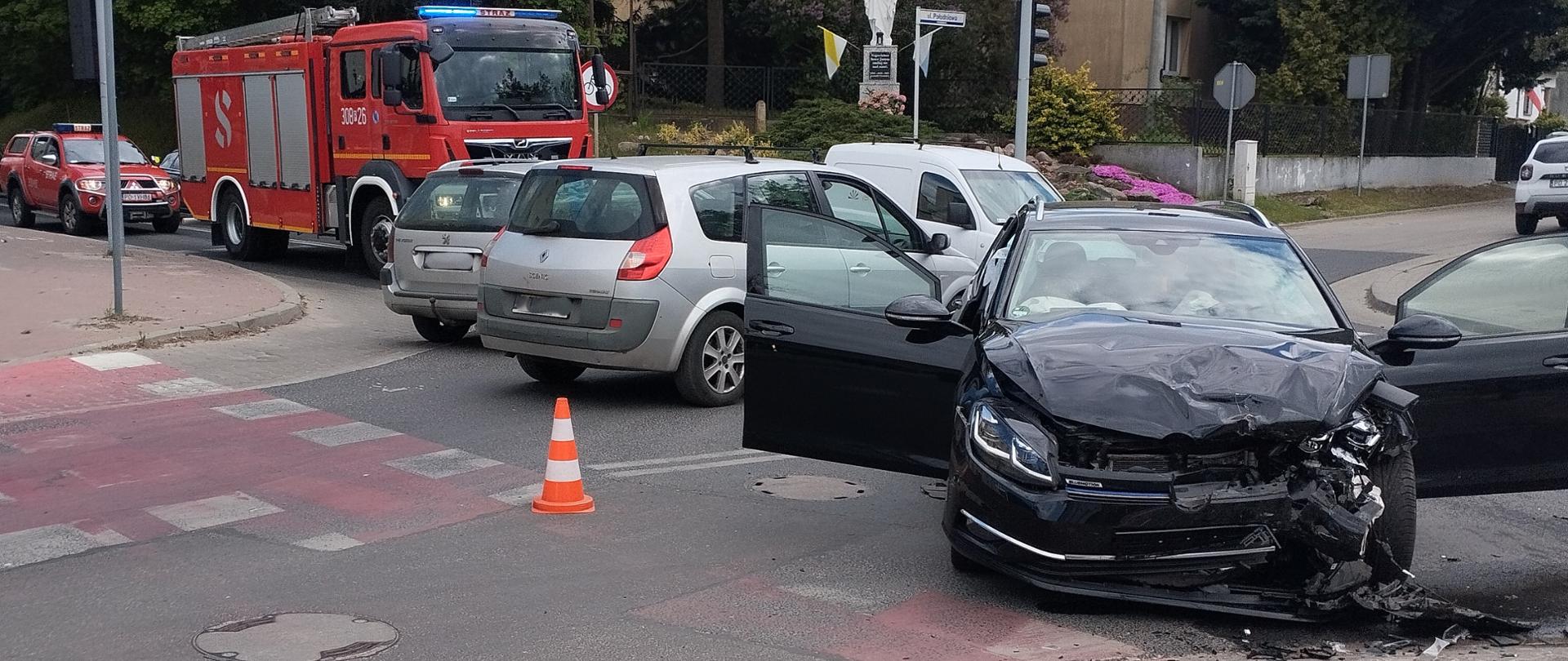 Samochód osobowy uszkodzony przód, w tle 2 samochody pożarnicze