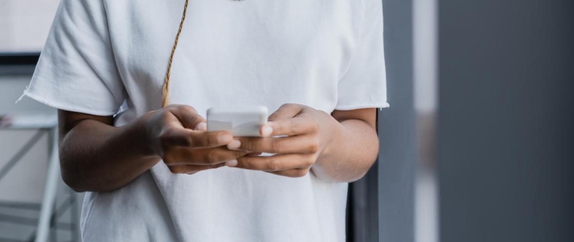 Na zdjęciu jest kobieta, która trzyma w dłoniach telefon.