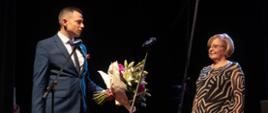 Zdjęcie przedstawiające Dyrektor PSM I stopnia w Jarocinie odbierającą na scenie kwiaty z okazji jubileuszu 45-lecia PSM I stopnia w Jarocinie.
