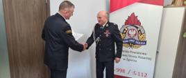 Komendant Powiatowy wręcza druhowi OSP pismo potwierdzające przyznanie świadczenia.