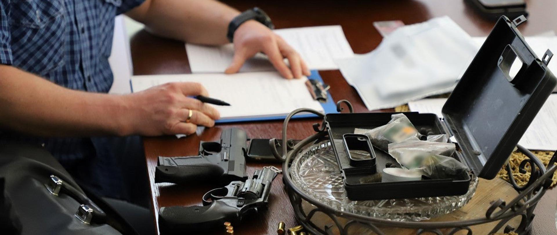 Funkcjonariusz podczas pisania protokołu, obok zatrzymana broń.