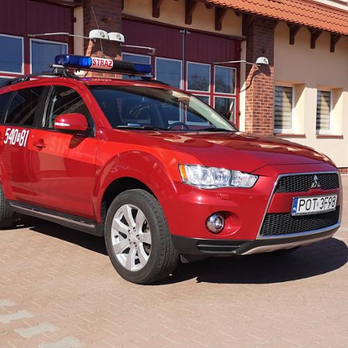Na zdjęciu samochód specjalny lekki kwatermistrzowski Mitsubishi Outlander na placu manewrowym przed garażami Jednostki Ratowniczo-Gaśniczej