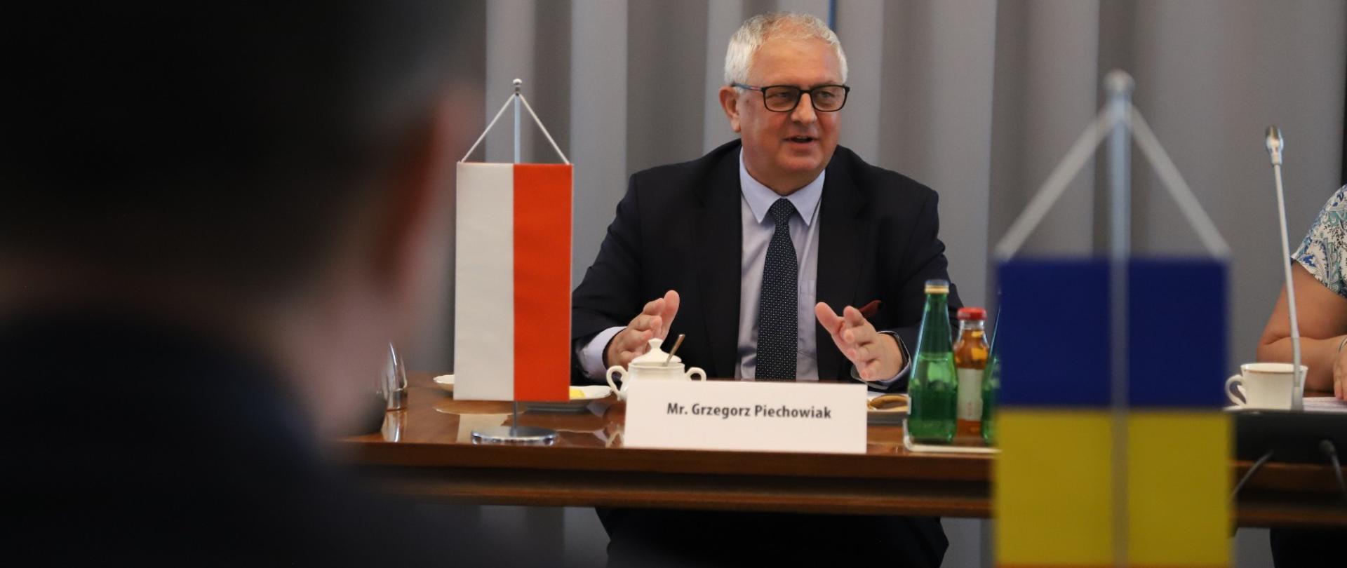 minister Piechowiak przy stole z flagami PL i RO