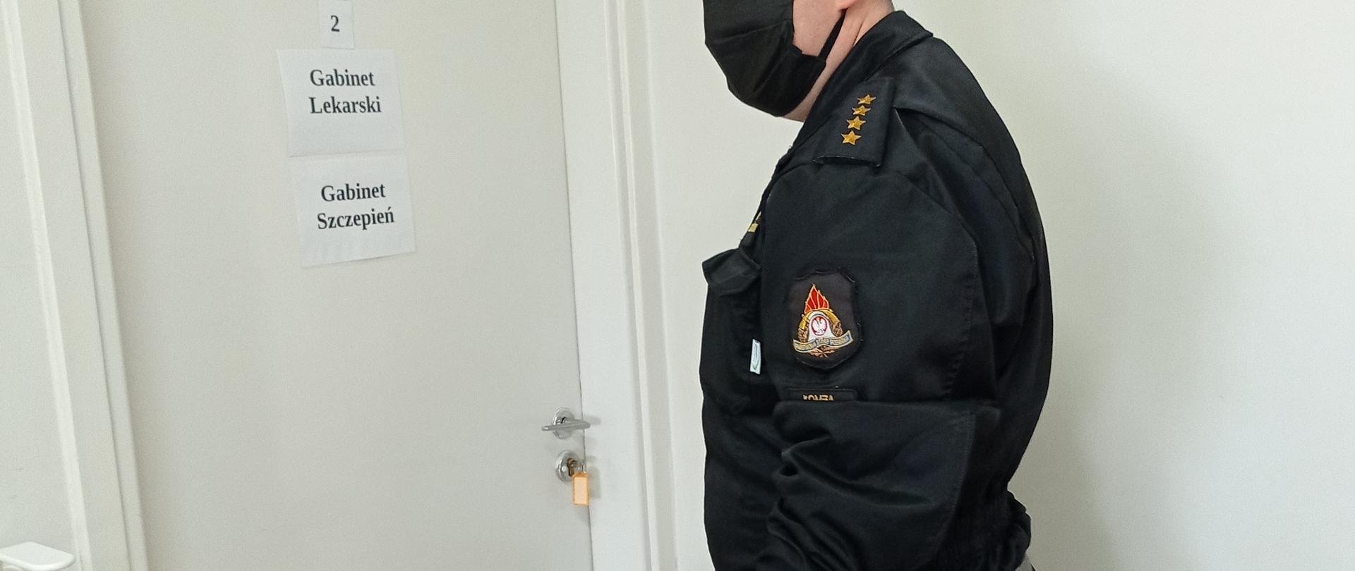 Na zdjęciu funkcjonariusz PSP oczekujący na zaszczepienie przed gabinetem lekarskim