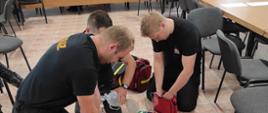 Trzech strażaków prowadzi resuscytację osoby poszkodowanej (manekina)