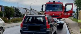 Widać uszkodzony samochód osobowy od tyłu, za nim samochód strażacki