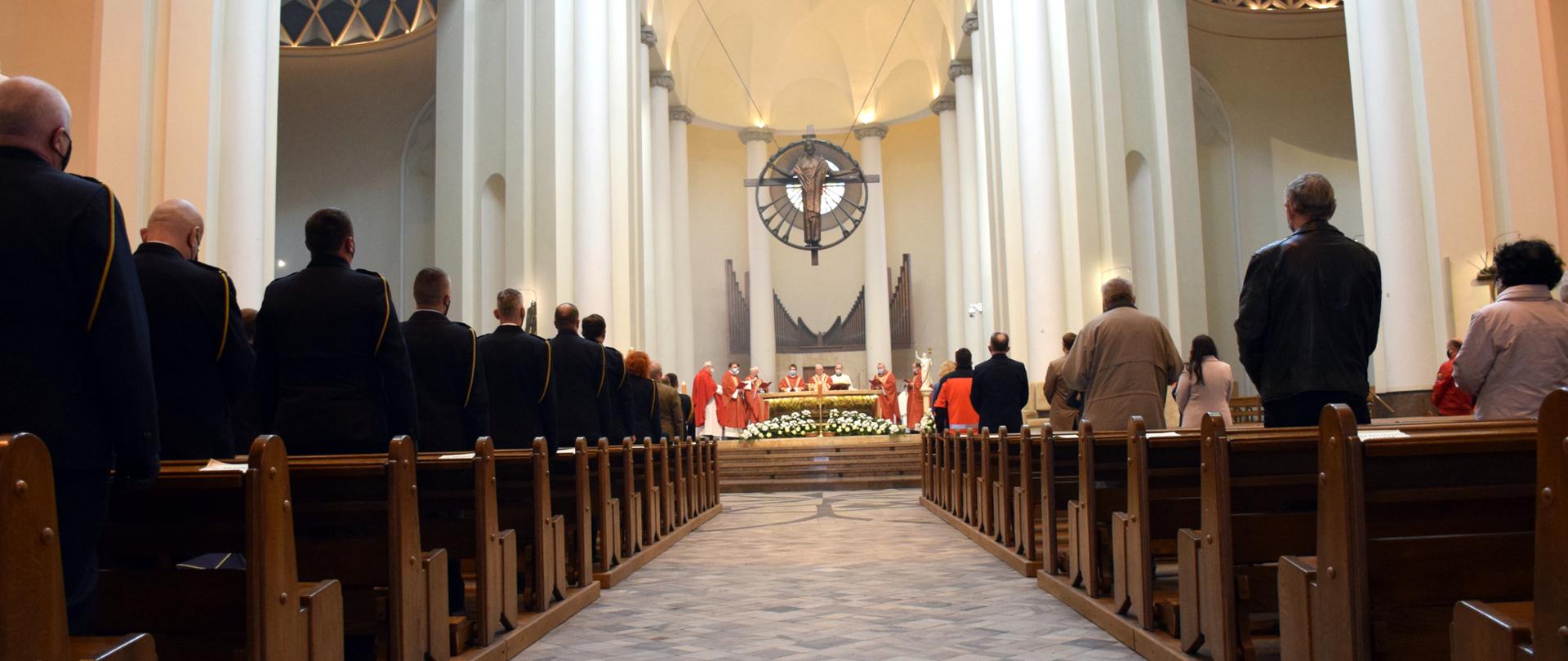Msza święta w intencji strażaków w w Archikatedrze Chrystusa Króla w Katowicach. Po lewej stoją strażacy w mundurach galowych po prawej zaproszeni goście i inni uczestnicy mszy. W głębi ołtarz.