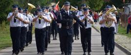 Maszerujący dowódca uroczystości, za nim widoczna orkiestra dęta
