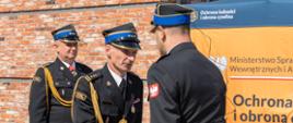 Na zdjęciu dowódca uroczystości młodszy kapitan Krystian Kaczmarek składający meldunek zastępcy Kujawsko Pomorskiego Komendanta Wojewódzkiego starszemu brygadierowi Robertowi Kulasińskiemu. W tle starszy brygadier Paweł Puchowski Komendant Powiatowy Państwowej Straży Pożarnej w Świeciu