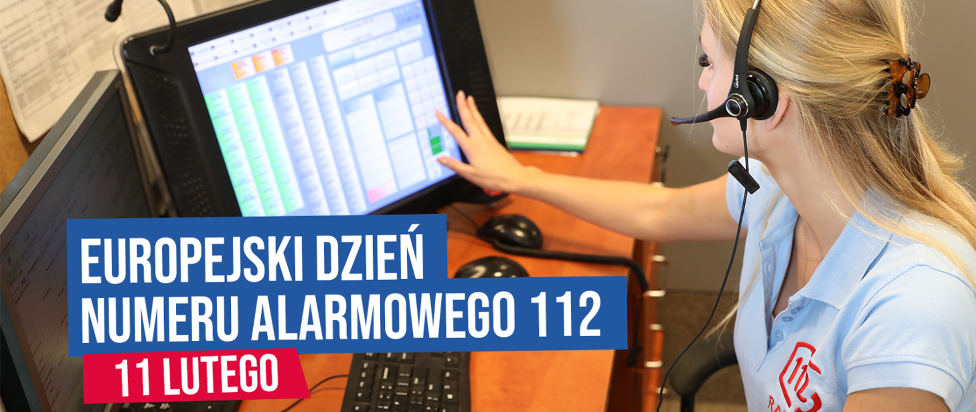 Kobieta operator numerów alarmowych siedzi przy biurku ze słuchawkami na głowie i wprowadza dane do systemu na dotykowym monitorze, pod spodem na niebieskim tle biały napis Europejski Dzień Numeru Alarmowego 112, poniżej na czerwonym tle biały napis 11 lutego