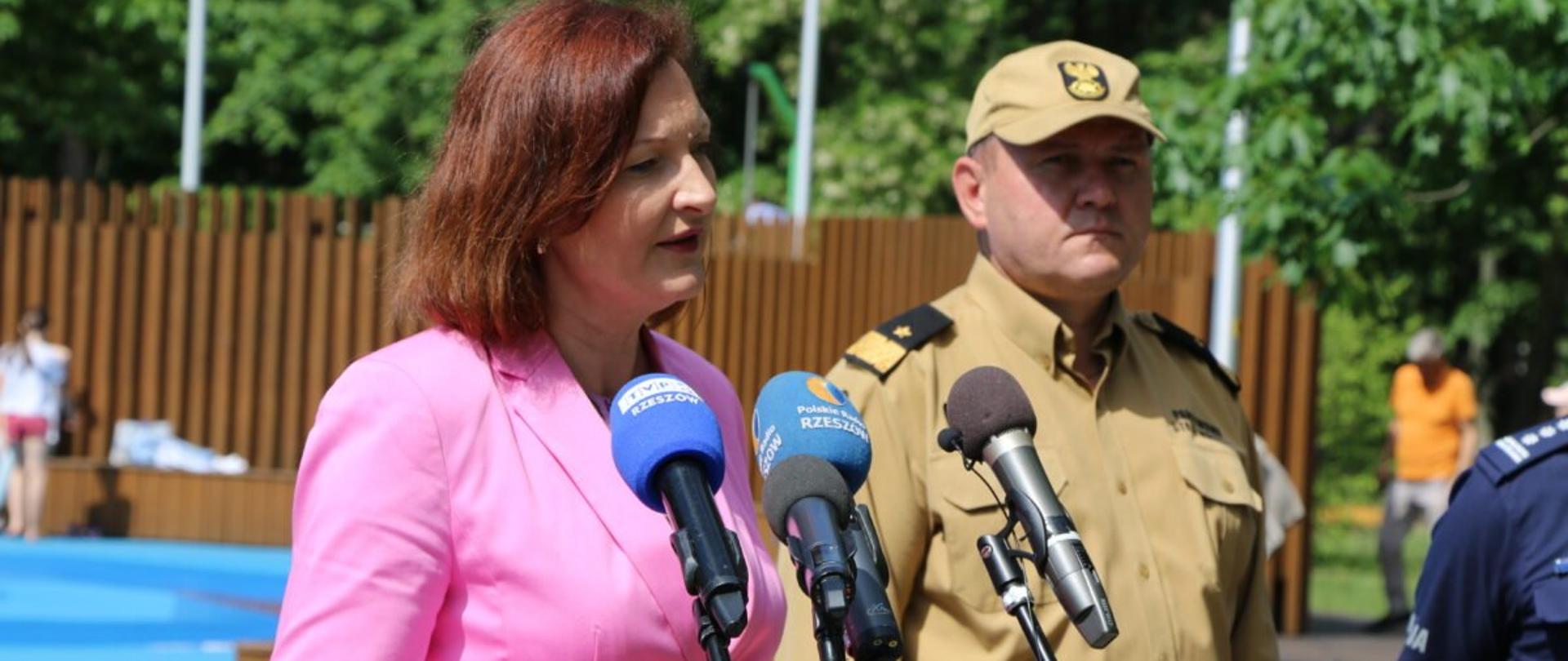 Wojewoda podkarpacki Ewa Leniart zabiera głos podczas briefingu prasowego na temat bezpiecznych wakacji. Po jej lewej stronie stoi komendant wojewódzki Państwowej Straży Pożarnej Andrzej Babiec.