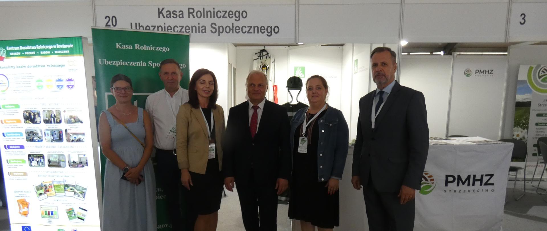 trzy kobiety i trzech mężczyzn stojących na tle stoiska KRUS