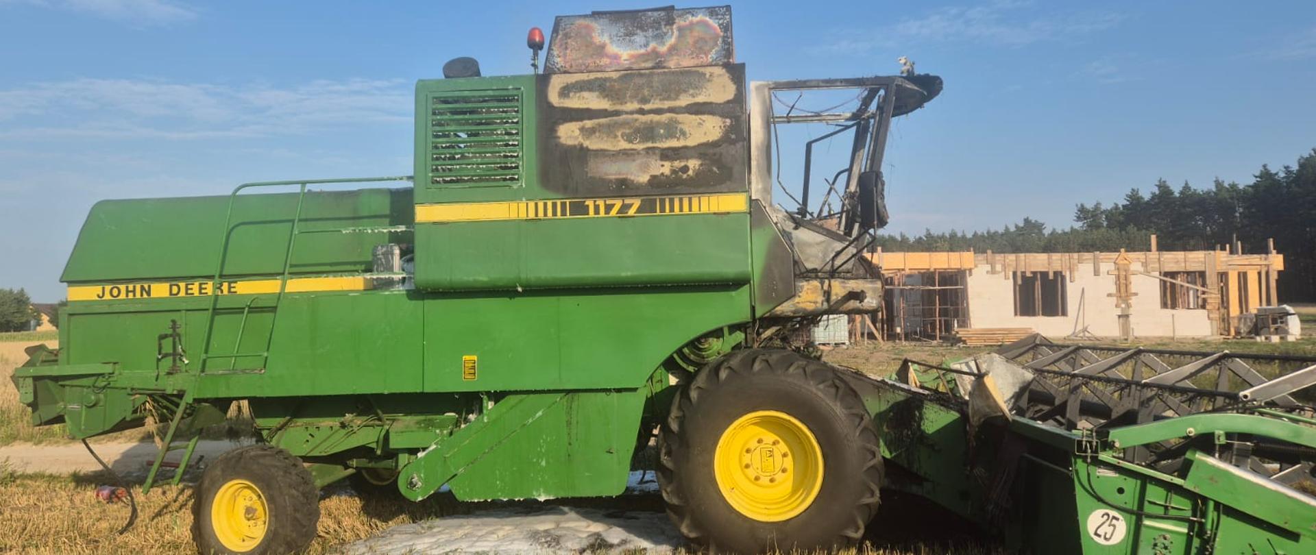  Na zdjęciu znajduje się spalony kombajn John Deere stojący na polu 