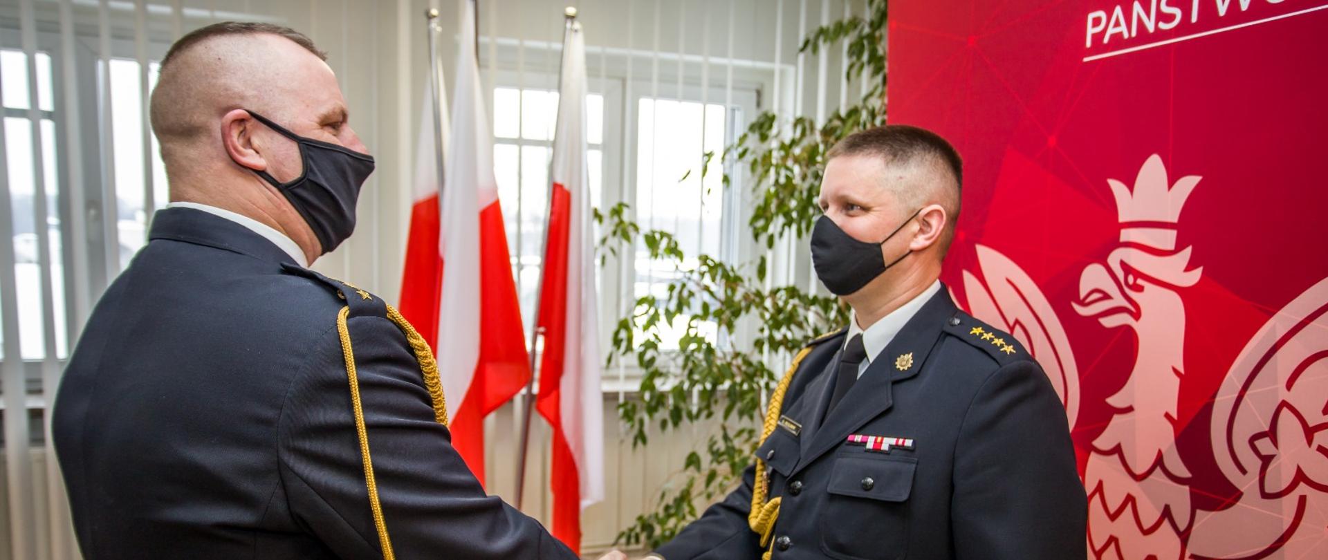 Dwóch funkcjonariuszy PSP w umundurowaniu wyjściowym, gratulujący sobie współpracę 