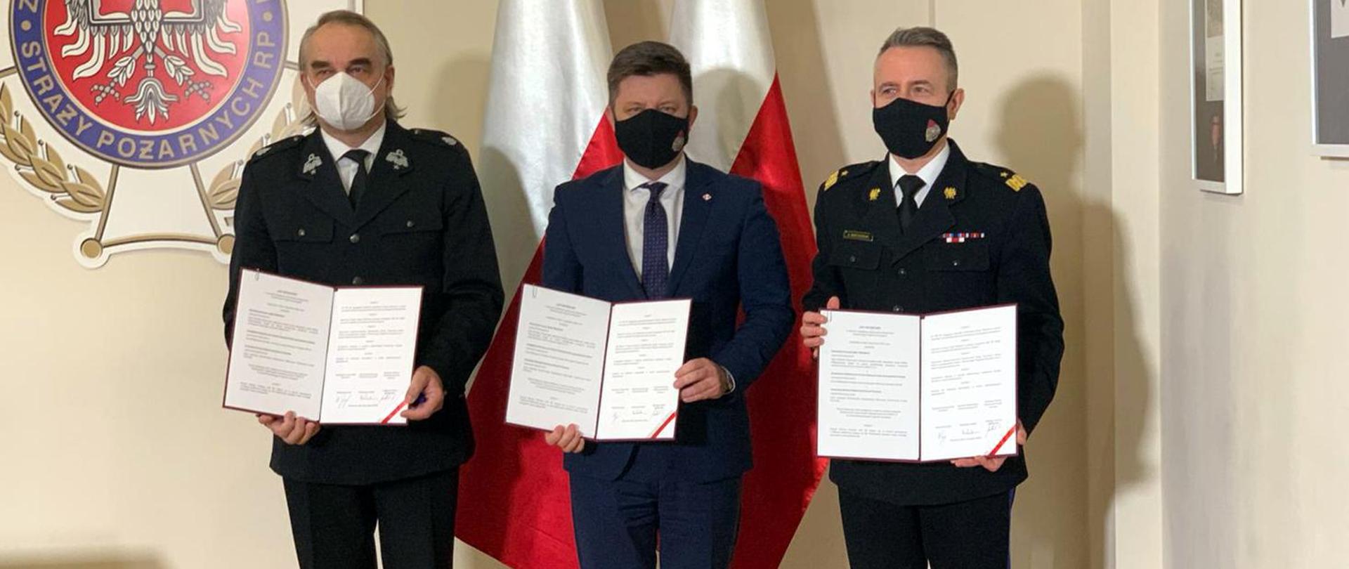 Trzech mężczyzn na tle flag państwowych po podpisaniu listu