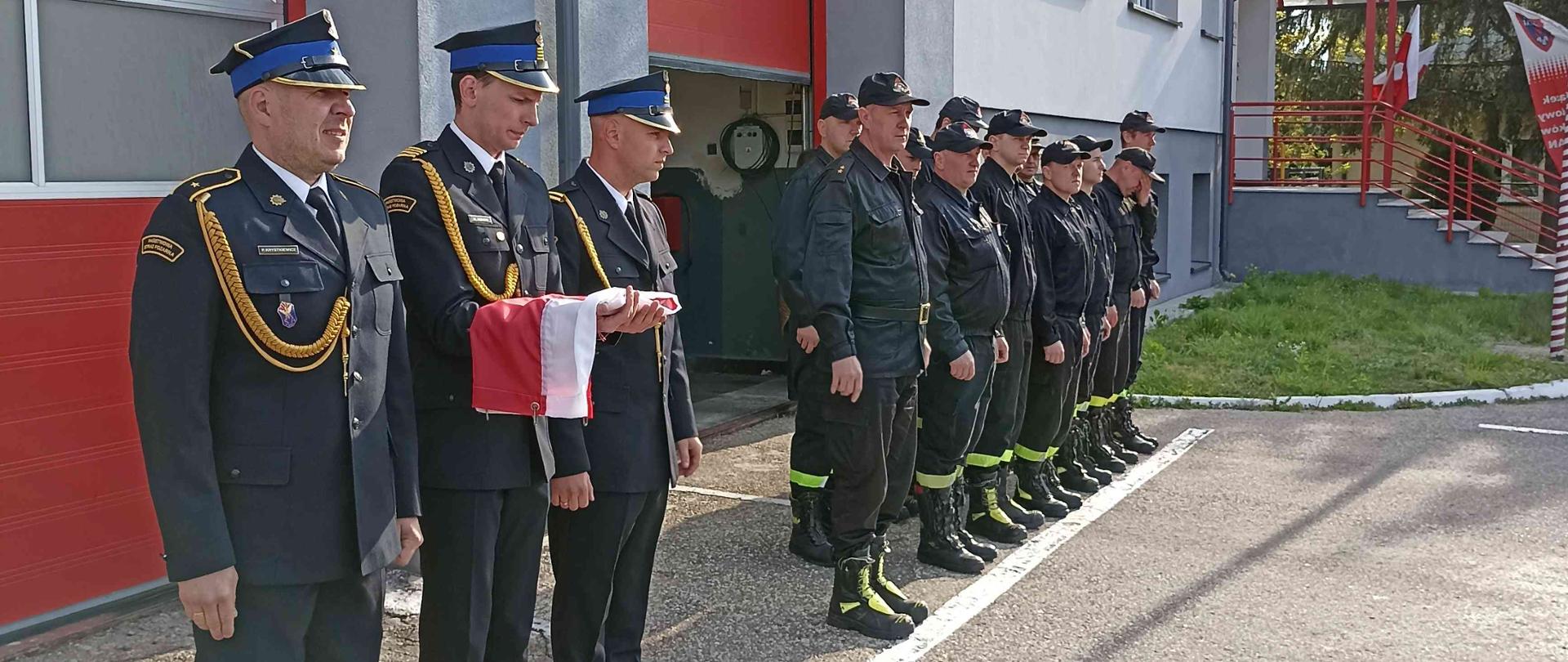 Strażacy stojący na uroczystej zmianie służby.