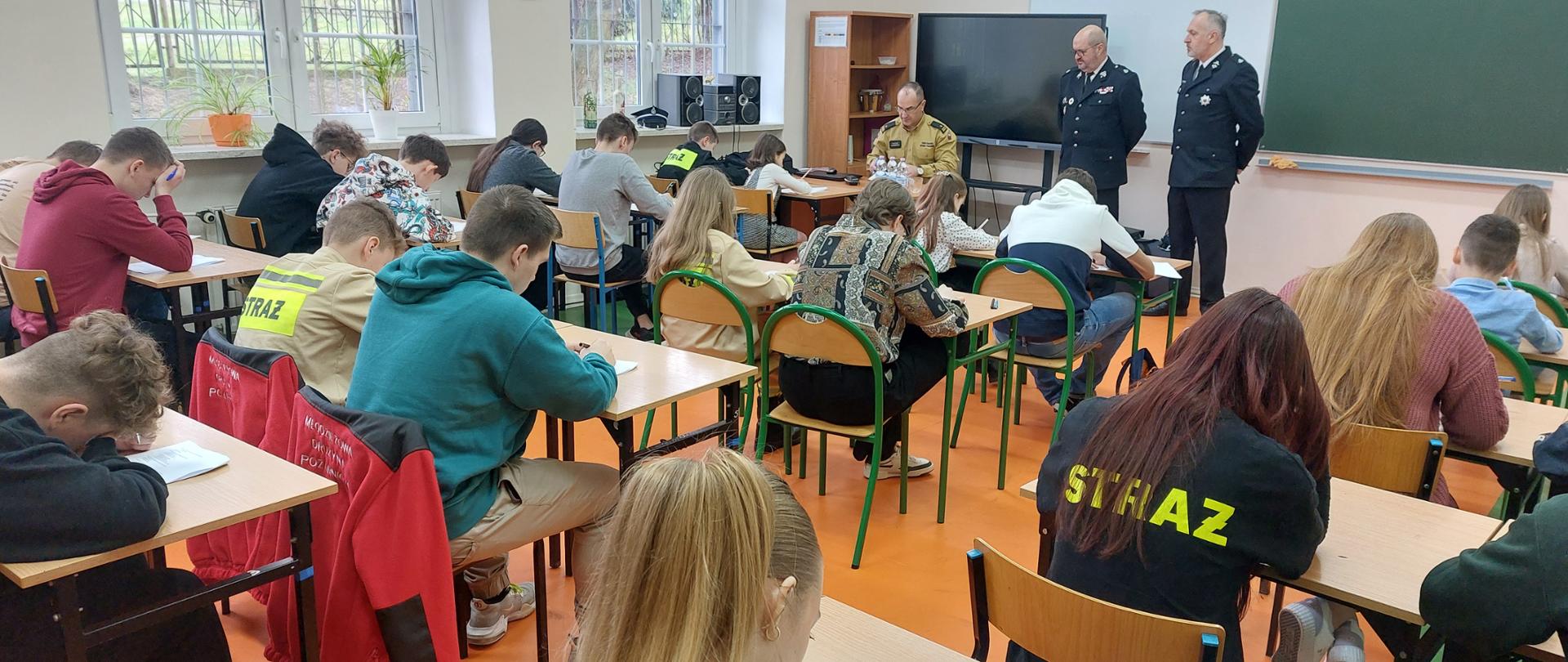 Zdjęcie przedstawia dzieci i młodzież podczas pisania testu podczas eliminacji miejskich OTWP. 