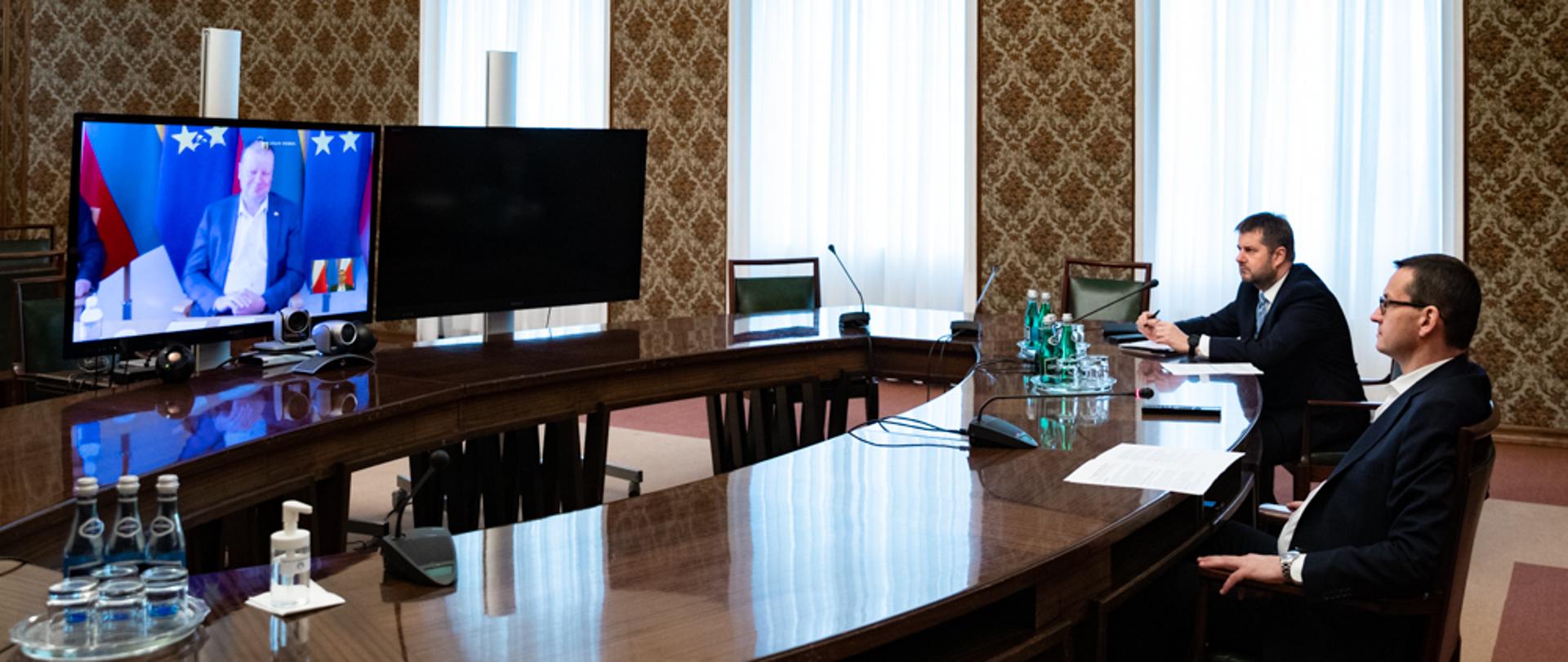 Premier Mateusz Morawiecki siedzi podczas wideokonferencji.