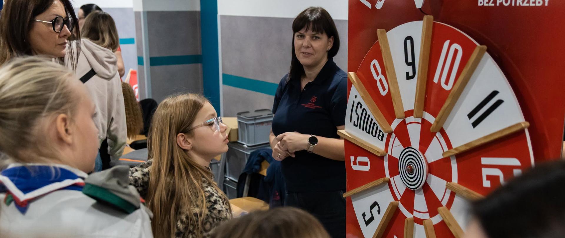 Na zdjęciu osoby w różnym wieku, dzieci, opiekunowie i prowadzący zajęcia - przed kołem Centrum Powiadamiania Ratunkowego w Bydgoszczy "112" - część edukacyjna 