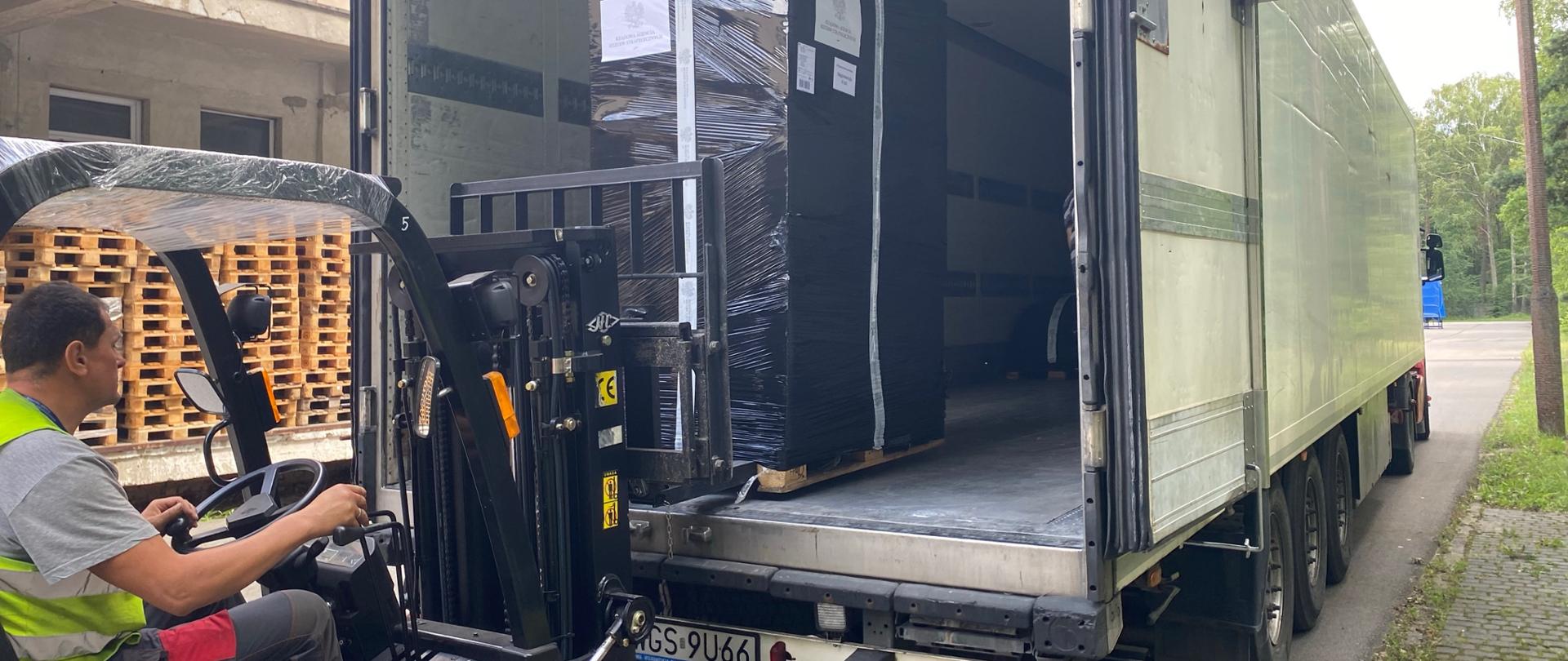 A man places the package in the truck with a forklift
