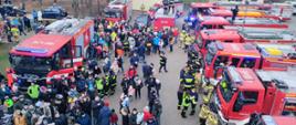 Na zdjęciu widać uczestników pikniku charytatywnego dla córki Naczelnika OSP Wola Zaradzyńska. Dookoła placu ustawione są samochody pożarnicze.