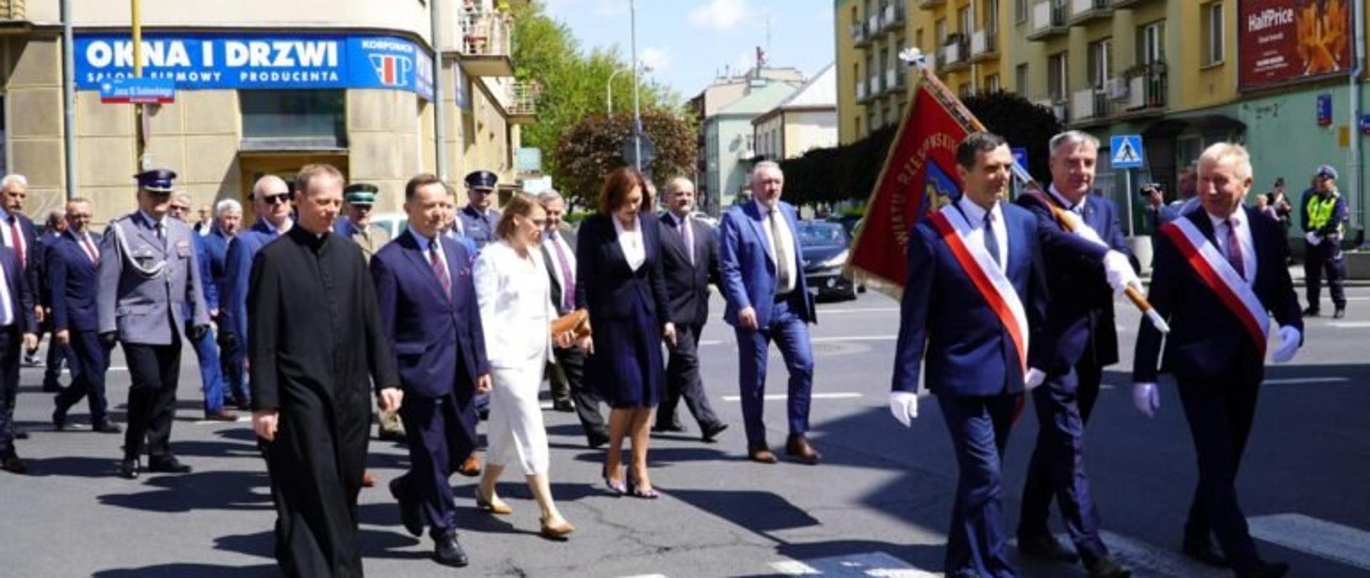 Uroczysty pochód z okazji Dnia Samorządu Terytorialnego. Na przodzie delegacja ze sztandarem, za nimi przedstawiciele władz województwa - m. in. wojewoda podkarpacki Ewa Leniart oraz marszałek Władysław Ortyl
